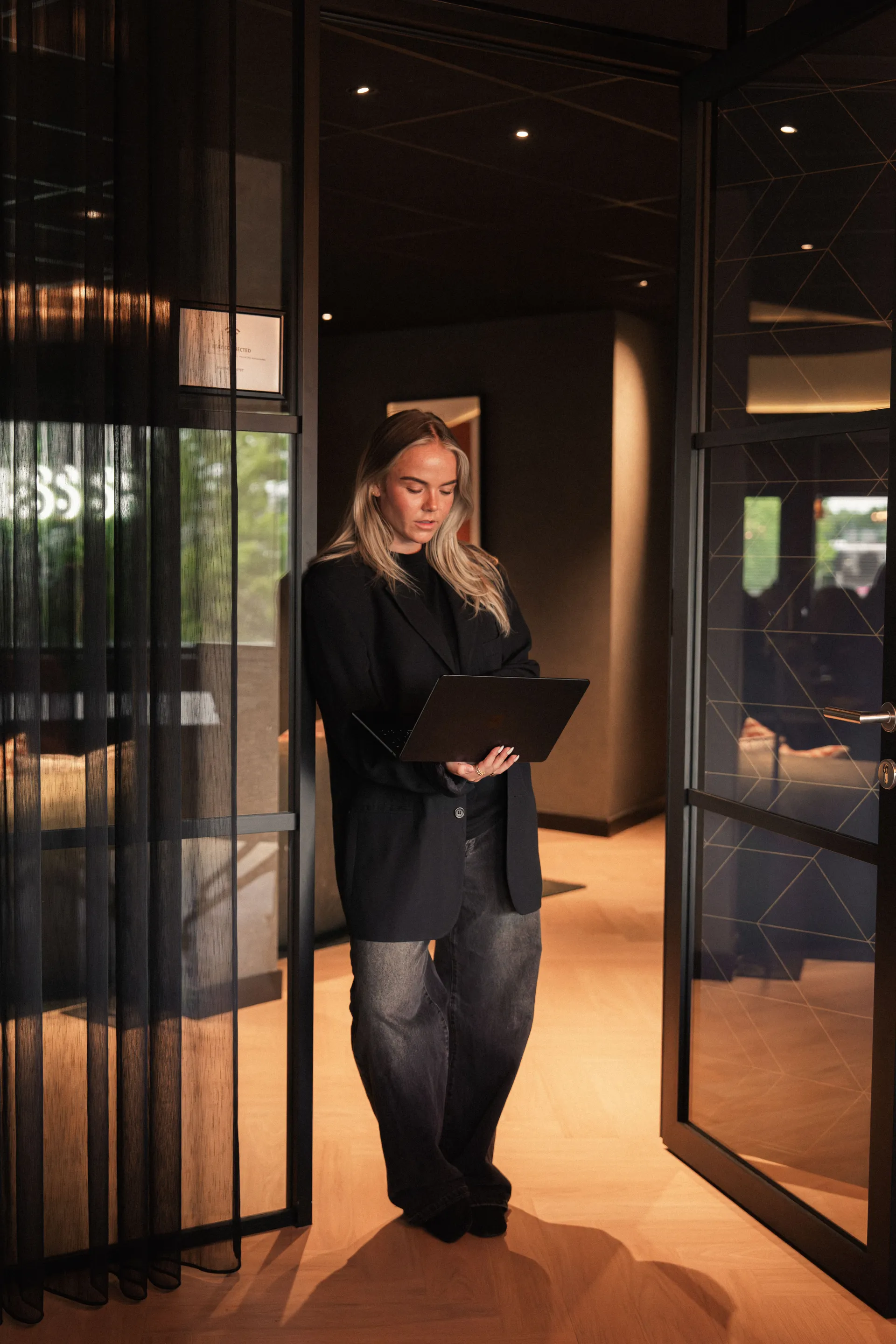 Een collega met laptop bij de glazen deur