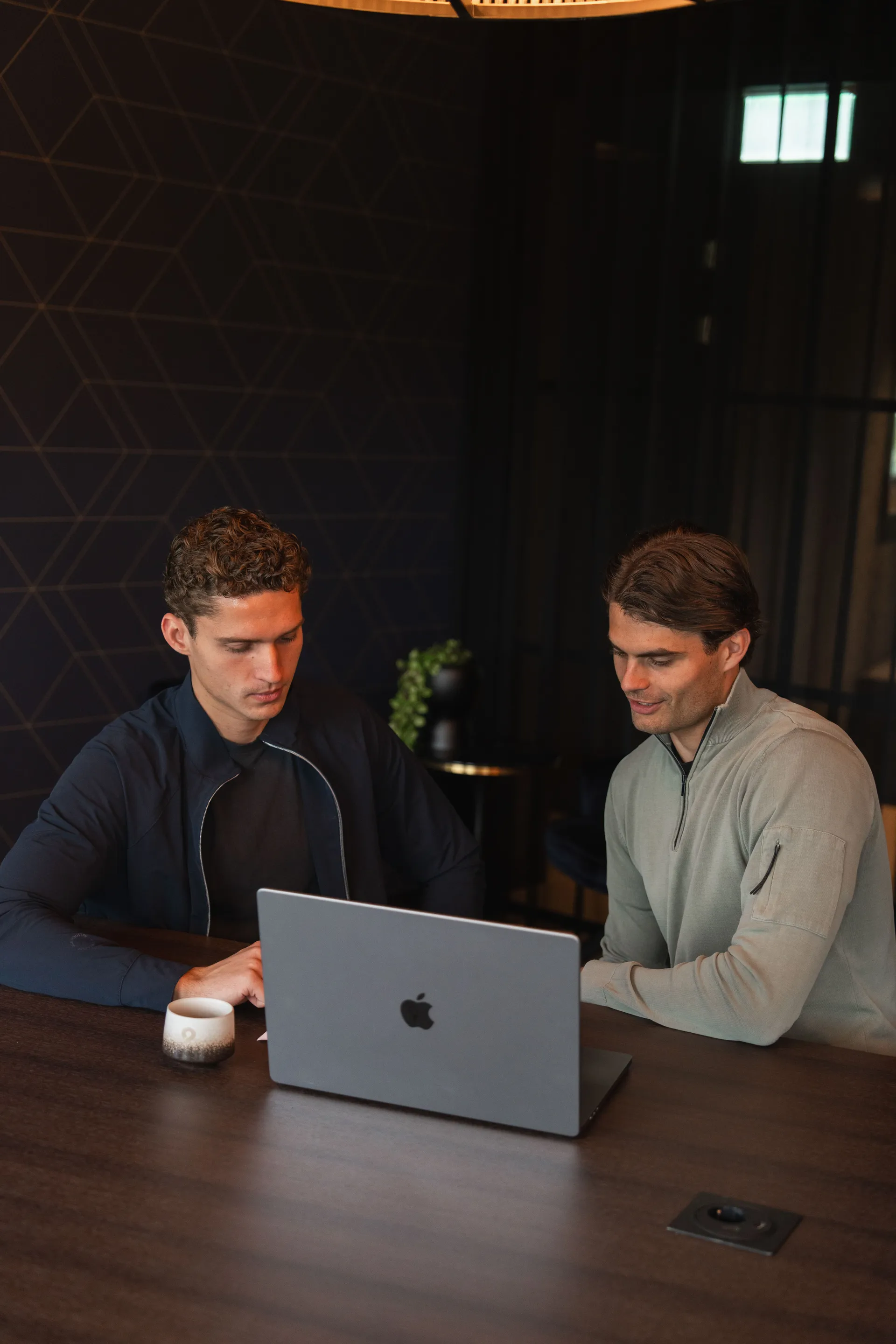 Twee collega’s overleggen samen achter een laptop